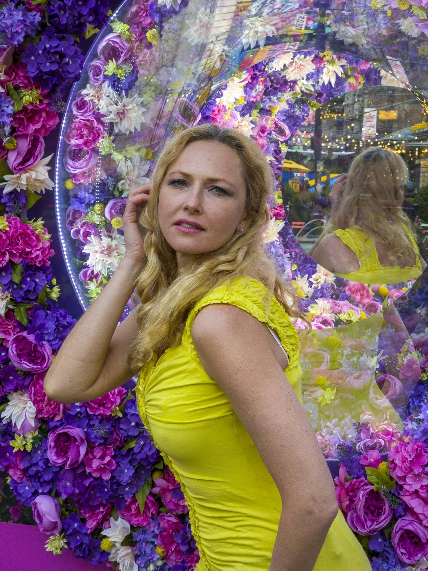 image of lady in front of a mirror surrounded by a flower wall
