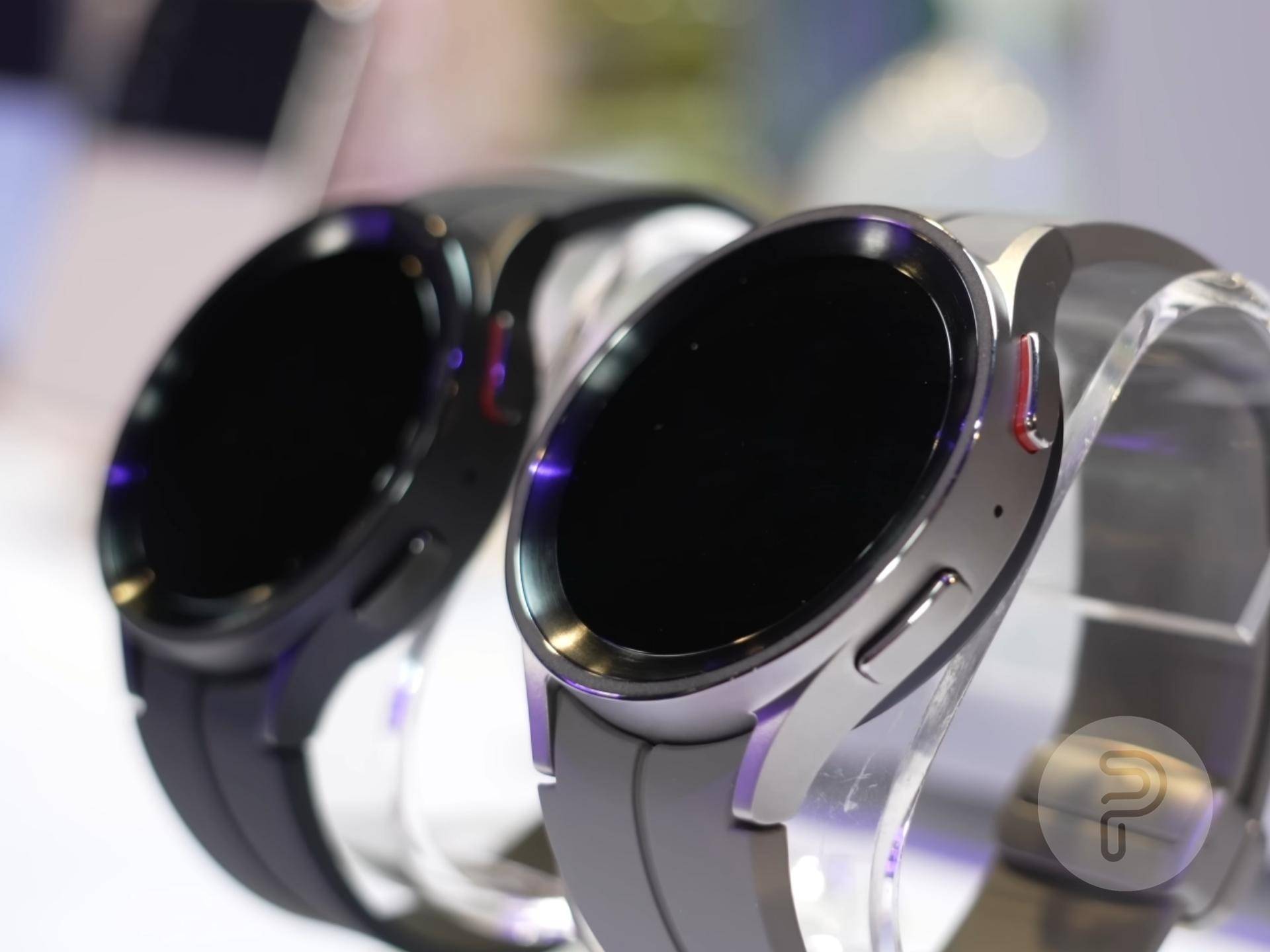 Galaxy Watch 5 Pro in Gray Titanium with Black Titanium variant in the background;  both placed on a clock stand