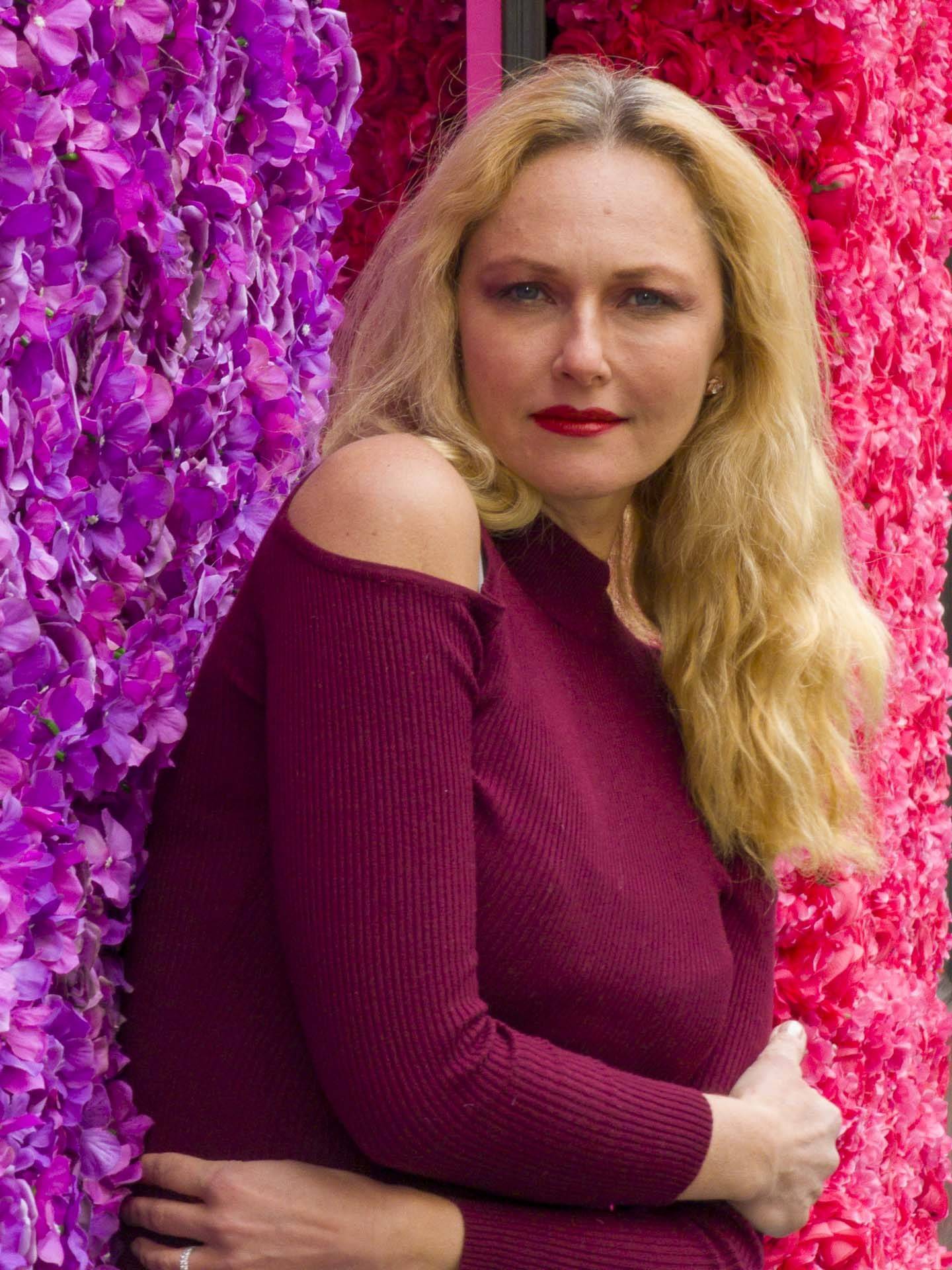 a lady in front of a flower wall