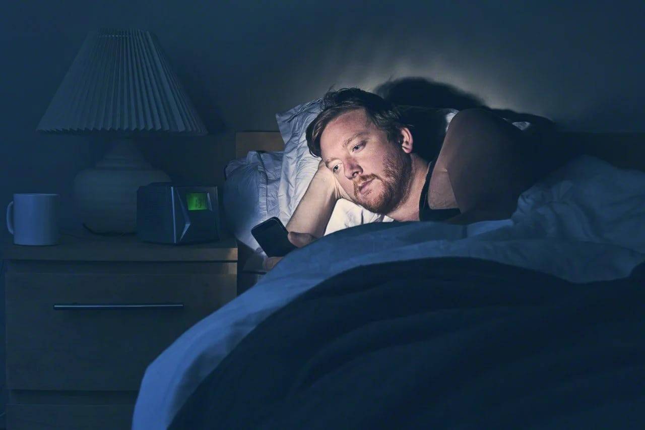 Men with smartphone in bed