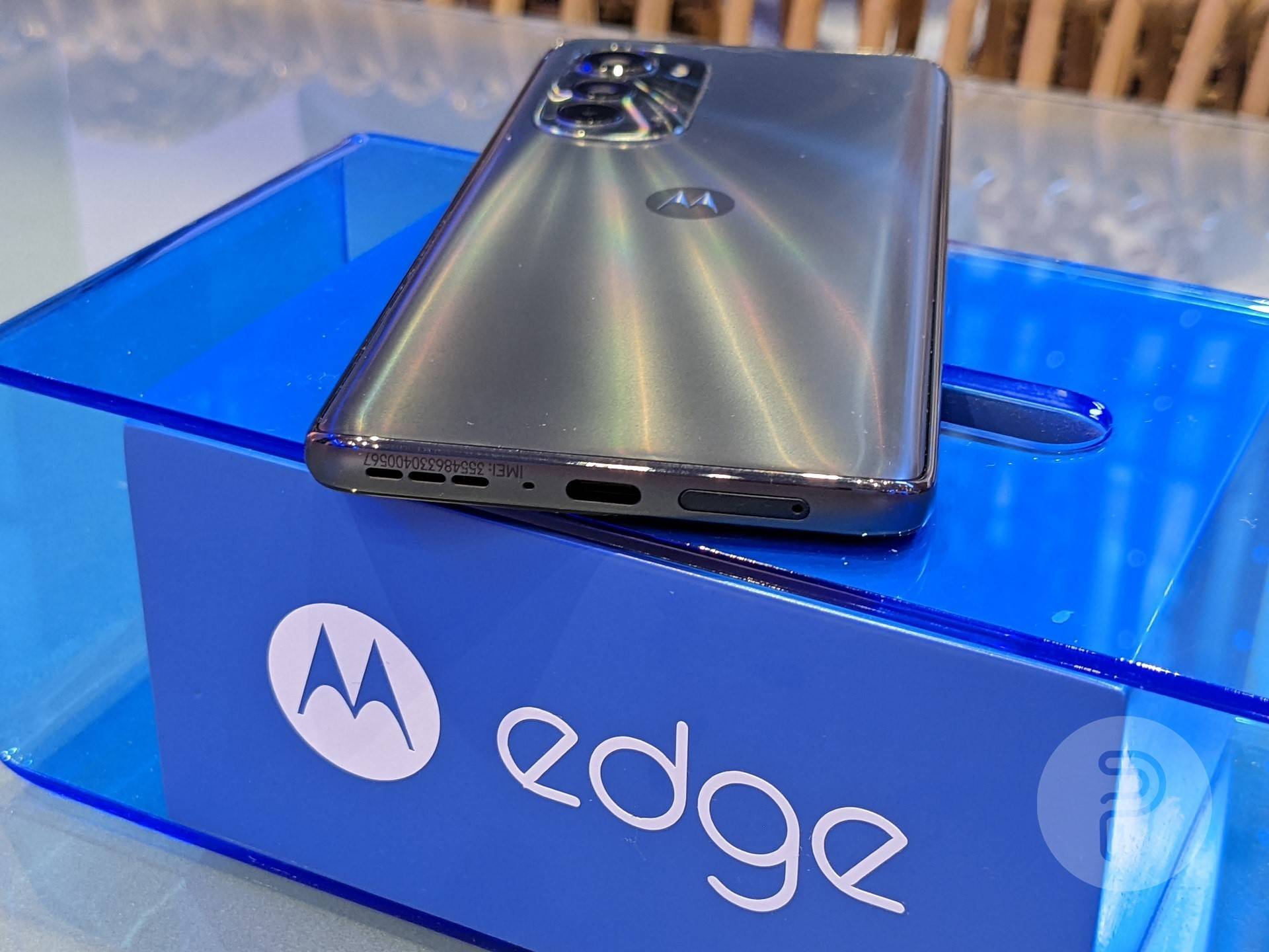 Motorola edge 2022 placed on a translucent blue box with a focus on its USB C port